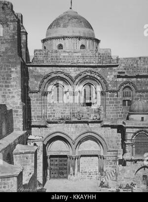 A photograph of the entrance to the Church of the Holy Sepulchre, the building is a stone work structure that has doorways and windows accented by stone archways, a dome rises above the second floor of the building, according to the traditions of some Christian sects the church houses the site where Jesus was crucified and the tomb where he was buried, it was constructed in the 4th Century, the church is located in the Christian Quarter of the Old City of Jerusalem, 1900. From the New York Public Library. Stock Photo