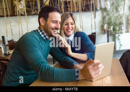 Young attractive couple having fun with tablet in cafe Stock Photo