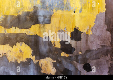 Old cracked concrete wall. Bright yellow painted wall with dark spots of plaster. Grunge background Stock Photo