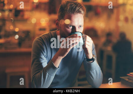 Young handsome man drinking coffee in bar Stock Photo