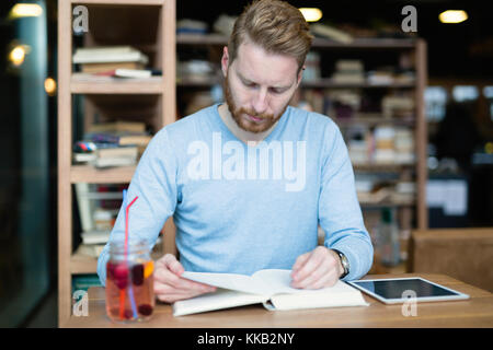 Young male student reading in coffee shop Stock Photo