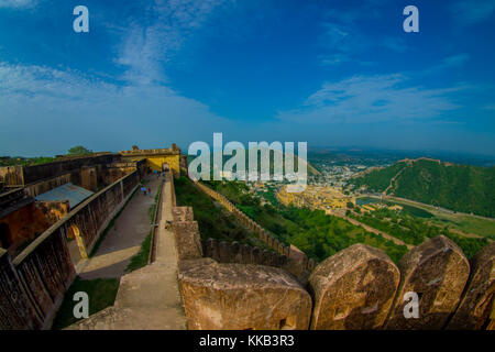 Beautiful landscape of Amber Fort with some people walking around, with green trees, mountains and small houses near Jaipur in Rajasthan, India. Amber Fort is the main tourist attraction in the Jaipur area Stock Photo