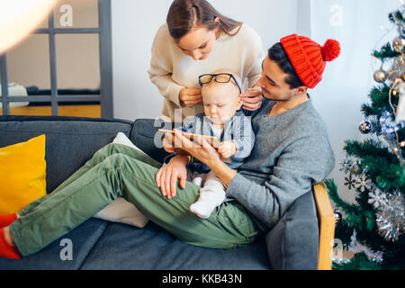 Family gathered around a Christmas tree, using a tablet Stock Photo