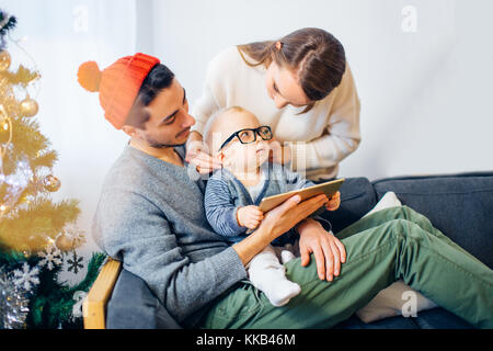 family sharing digital tablet near wood stove on winter evening Stock Photo