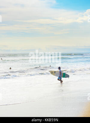 CANGGU, BALI ISLAND, INDONESIA - JAN 19, 2017: Surfer going to surf in the ocean. Bali island is one of the worlds best surfing destinations Stock Photo