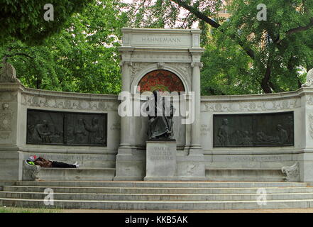 A homeless man taking a nap on the bench of Samuel Hahnemann Monument in Washington, DC Stock Photo