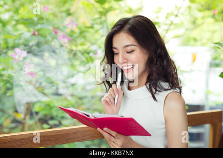 Beautiful asian girl writing notes in a desk at home Stock Photo