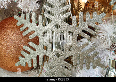 Close-up of silver glitter snowflake shaped Christmas ornament with gold gritter ball shaped ornament in background Stock Photo