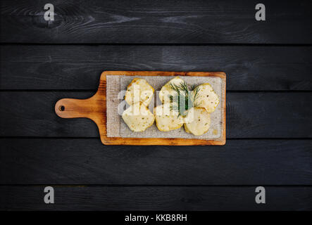 Bread with cheese. Fried garlic croutons with dill. On a wooden board. Top view. Black wooden background Stock Photo