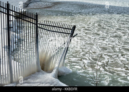 winter ice formations on lake Michigan with snow covered iron fence in foreground Stock Photo