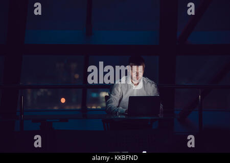 Businessman working on laptop in night office. Stock Photo