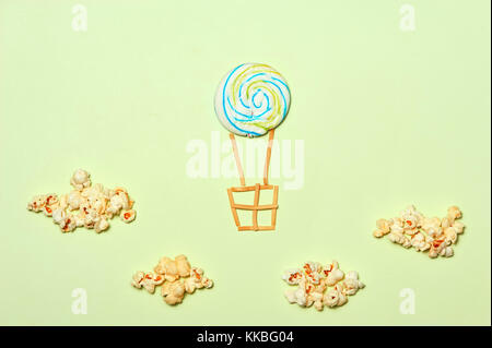 Creative Travel Concept - Top View Sweet Candy Air Balloons and Popcorn Clouds on Blue Background. Minimal Travel Fun Concept. Flat Lay Stock Photo