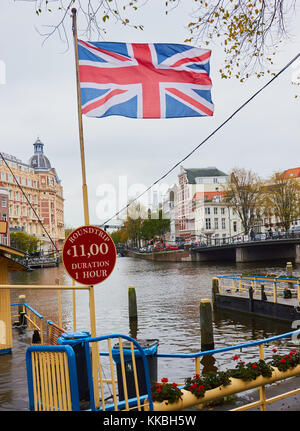 Union Jack flying next to sign for Canal trip, Amsterdam, Holland Stock Photo