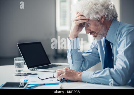 Stressed exhausted businessman sitting at office desk, failure and loss concept Stock Photo