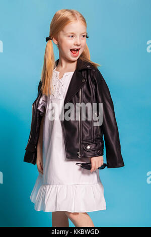little girl with tails in stylish clothes on blue background Stock Photo
