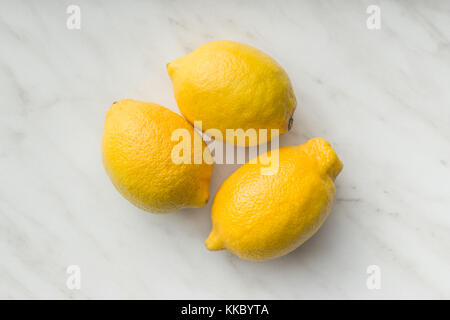 Three yellow lemons on table. Top view. Stock Photo