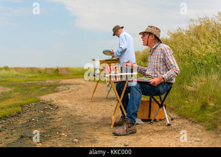 A pair of Artists painting an outdoor scene on the coast at Walberswick. Stock Photo