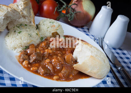A plate of traditional Turkish White Bean Stew, Etli kuru fasulye, with Orzo pilau rice and crusty bread. Stock Photo