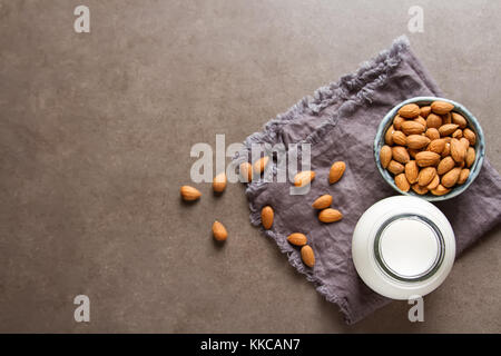 Dairy alternative milk. Almond milk in a glass bottle and fresh nuts over a gray background, selective focus. Clean eating, dairy-free, vegan, vegetar Stock Photo