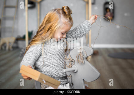 Merry Christmas and Happy Holidays. Cheerful child girl opening a Christmas present. Stock Photo
