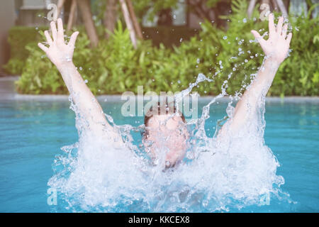 Man is swimming and playing in the swimming pool with spray. Stock Photo
