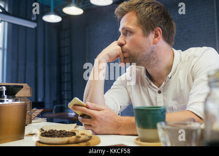 A young man sits in a cafe and waits for a business partner in solitude. Stock Photo