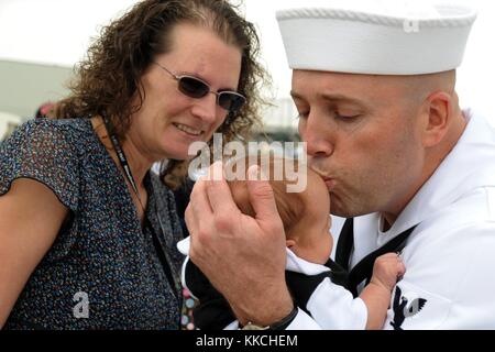 Tessa Ooley watches her husband, Gas Turbine Systems Technician 1st Class Daniel Ooley assigned to the guided-missile destroyer USS Halsey DDG 97, kiss his daughter for the first time during a homecoming celebration at Naval Base San Diego, San Diego. Image courtesy Mass Communication Specialist 2nd Class Rosalie Garcia/US Navy. 2012. Stock Photo