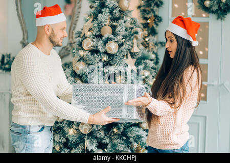 Cropped shot of a man surprising his girlfriend with a Christmas gift. Stock Photo