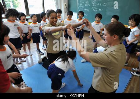 Hull Maintenance Technician 3rd Class Jane Clark and Boatswain's Mate Seaman Brittany Chiles, assigned to the Arleigh Burke-class guided-missile destroyer USS McCampbell DDG 85, play a game with Ogamo Elementary School first graders, Shimoda, Japan. Image courtesy Mass Communication Specialist Seaman Declan Barnes/US Navy. 2012. Stock Photo