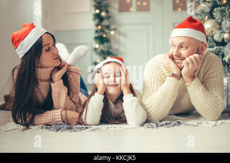 Family in Christmas Santa hats lying on bed. Mother father and baby having fun Stock Photo