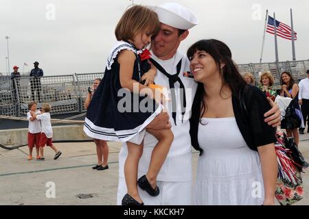 Gunners Mate 2nd Class Kenny Klein receives the first hug from his daughter and wife, Angeleia, during the guided-missile destroyer USS Halsey DDG 97 homecoming celebration at Naval Base San Diego. Image courtesy Mass Communication Specialist 2nd Class Rosalie Garcia/US Navy, 2012. Stock Photo