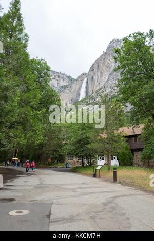 View of Yosemite Falls from Yosemite Village in Yosemite National Park, on an overcast, cloudy day, with tourists walking on a path in the background, Yosemite Valley, California, 2016. Stock Photo