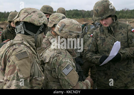 A Polish soldier with the 2nd Engineer Battalion, 5th Engineer Regiment, goes over how the Polish army lays out anti-tank mines with U.S. Soldiers assigned to the 82nd Brigade Engineer Battalion, 2nd Armored Brigade Combat Team, 1st Infantry Division, at the Drawsko Pomorskie Training area during a 13-day training event called Bull Eagle near Oleszno, Poland, on Nov. 27, 2017. The 2nd ABCT assures NATO allies and deters aggression by demonstrating and sustaining maximum proficiency and readiness in its warfighting functions, tasks and drills by conducting training with U.S. allies throughout a Stock Photo