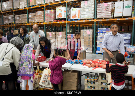 President Barack Obama, along with First Lady Michelle Obama, daughters Sasha and Malia, and Craig Robinson, participates in a service project at the Capital Area Food Bank in Washington, D.C., Nov. 21, 2012. (Official White House Photo by Pete Souza)  This official White House photograph is being made available only for publication by news organizations and/or for personal use printing by the subject(s) of the photograph. The photograph may not be manipulated in any way and may not be used in commercial or political materials, advertisements, emails, products, promotions that in any way sugge Stock Photo