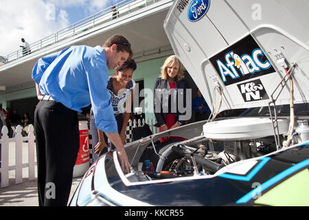 First Lady Michelle Obama and Dr. Jill Biden watch as NASCAR driver Carl Edwards points out features under the hood of his backup car before the start of the Ford 400 race at the Homestead-Miami Speedway in Homestead, Fla., Nov. 20, 2011. Stock Photo