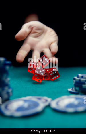 Image of man throwing five red dice on table with chips in casino Stock Photo