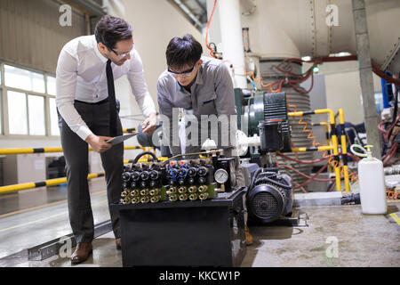 Businessman and engineer checking machine in the factory Stock Photo