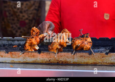 Three marinated chicken legs or quarters being cooked slowly over charcoal in a traditional way at the National Crafts Mela, Kalagram, India. Stock Photo