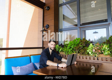 Happy businessman looking at camera working with laptop and talk Stock Photo