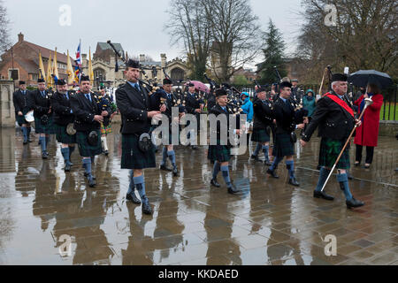 Pipe band marching & playing in rain during parade near York Minster on 50th anniversary of British withdrawal from Aden - Yorkshire, England, GB, UK. Stock Photo