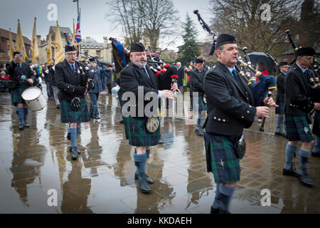 Pipe band marching & playing in rain during parade near York Minster on 50th anniversary of British withdrawal from Aden - Yorkshire, England, GB, UK. Stock Photo