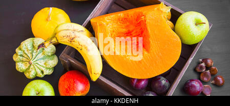 Autumn harvest with pumpkins, squash, plums, apples and chestnuts in a wooden tray Stock Photo