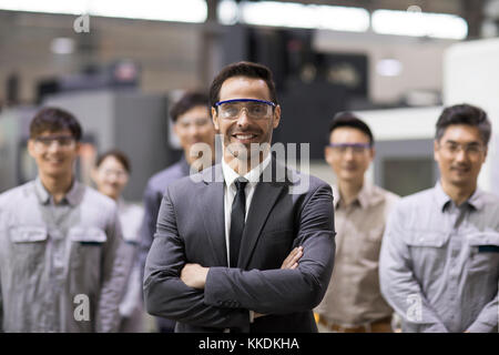 Confident businessman and engineering team in the factory Stock Photo
