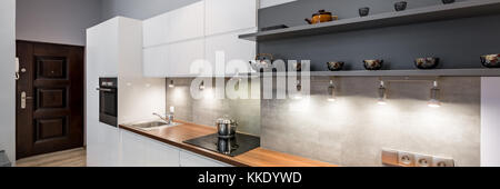 Contemporary white kitchen with wooden countertop and led lighting, panorama Stock Photo