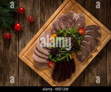 sliced smoked meat on a cutting board decorated with vegetables, top view Stock Photo