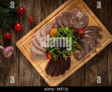 sliced meatloaf on a wooden tray and is decorated with vegetables, top view Stock Photo