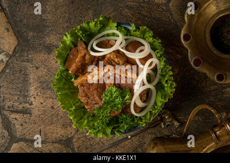 oriental dishes on decorative old tiles. fried meat and jug on decorative old paving stones Stock Photo