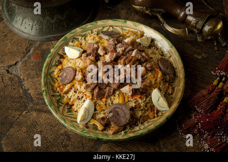 oriental dishes on decorative old tiles. pilaf and pitcher on decorative old paving stones Stock Photo