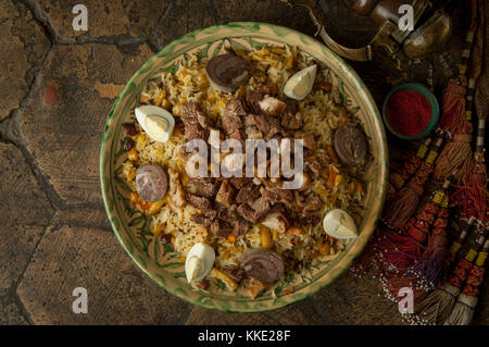 oriental dishes on decorative old tiles. pilaf and pitcher on decorative old paving stones Stock Photo