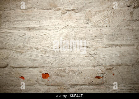Old grunge white painted brick wall background texture with dirty paint and portions of the red clay showing through where it has flaked off Stock Photo